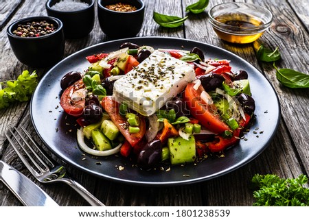 Fresh Greek salad - feta cheese, tomatoes, cucumber, red pepper, black olives and onion on wooden table 