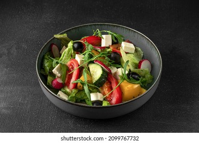 Fresh Greek Salad In A Gray Bowl On A Dark Background, Side View