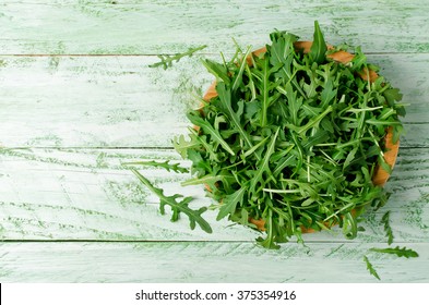 Fresh green arugula in bowl on wooden table. Arugula is rich in vitamins and trace elements