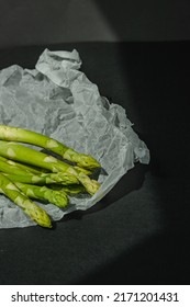 fresh green asparagus lies on a white parchment on a dark gray background. proper nutrition. Lifestyle. place for text