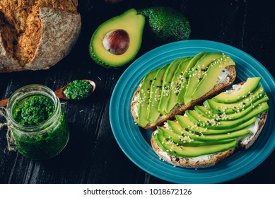 Fresh green Avocado sandwich on dark rye bread made with fresh sliced avocados from above. Avo toast, avo sandwich, vegan and vegetarian
