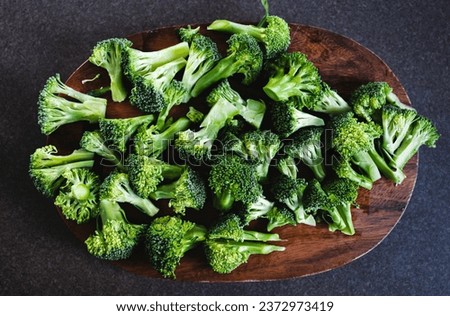 fresh green broccoli florets on wooden cutting board on kitchen counter, concept of simple natural healthy ingredients