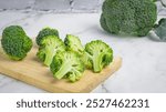 Fresh green broccoli on wooden cutting board, crispy texture, delicious and healthy food, on white marble background.