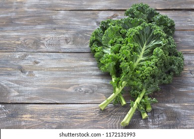Fresh green curly kale leaves on a cutting board on a wooden table. selective focus. free space. rustic style. healthy vegetarian food
