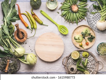 Fresh Green Food Cooking Concept. Various Seasonal Vegetables On Table With Kitchen Tools And Spoon , Top View. Round Wooden Cutting Board Copy Space. Healthy Organic Food. Paleo Dieting. Vegetarian