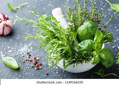 Fresh green garden herbs in mortar bowl and spices on black stone table. Thyme, rosemary, basil, and tarragon for cooking. - Powered by Shutterstock