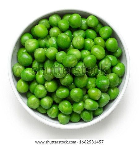 Fresh green garden peas in a white ceramic bowl isolated on white. Top view.
