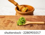 Fresh, green garlic leaves paste called mujdei in romanian cuisine, made in a wood pestle mortar, side view close up