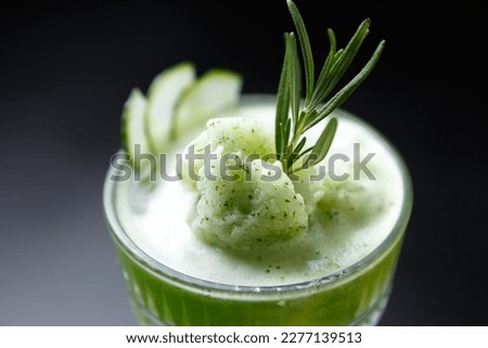 Fresh green gimlet cocktail prepared with rum, vodka, sliced cucumbers and rosemary herb. Popular summer long drink with alcohol