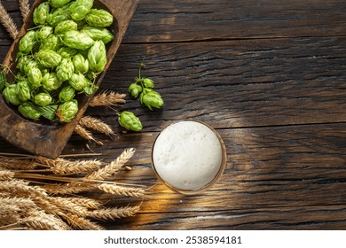 Fresh green hops flowers, ripe golden wheat ears and glass of beer with white beer foam on wooden table. Top view. - Powered by Shutterstock