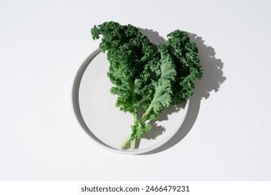 Fresh green kale leaves on a white plate. Top view - Powered by Shutterstock