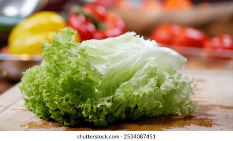 Fresh green lettuce leaves lie on a wooden cutting board next to the yellow bell pepper and red cherry tomatoes on a green table - Powered by Shutterstock