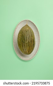 Fresh Green Melon Or Cantaloupe Melon In An Oval Dish Or Plate On A Green Mint Background. Directly Above. Selective Focus.