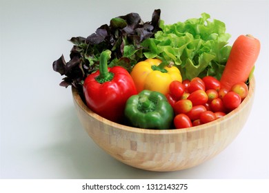 Fresh green oak lettuce, red oak lettuce, carrot, bell peppers and cherry tomatoes in a wooden bowl on white background, Mixed salad ingredients, Vegetables salad - Powered by Shutterstock