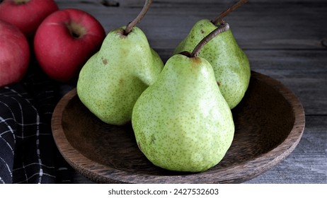 Fresh Green Pear (Pyrus) or green packham pear on wood tray and Red Fuji Apple (Malus pumila, Fuji) at old table with black napkin . Harsh light. Healthy Food. - Powered by Shutterstock