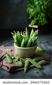Fresh green peas on the table in a grey pot on dark background 