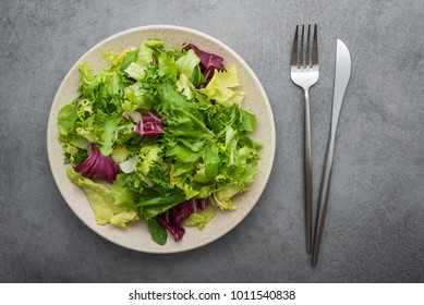 Fresh Green Salad Mix With Lettuce And Arugula On Stone Table. Diet Concept Background. Vegan Food. Top View