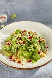Fresh Green Salad With Pineapple And Pomegranate Seeds On A Stony Background.