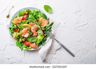 Fresh green salad with smoked salmon, cherry tomatoes and capers on white table background close up - Powered by Shutterstock