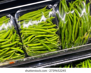 Fresh green string beans in clear plastic containers supermarket produce section display