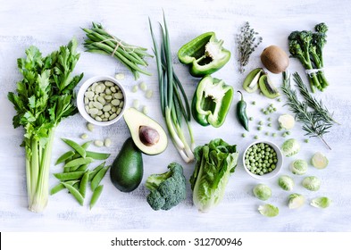 Fresh green vegetables variety on rustic white background from overhead, broccoli, celery, avocado, brussel sprouts, kiwi, pepper, peas, beans, lettuce, - Powered by Shutterstock