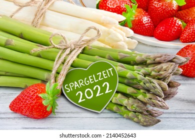 Fresh green and white asparagus with German label and season 2022 on wooden background closeup