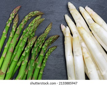 Fresh green and white asparagus on a dark slate background, comparison of asparagus varieties