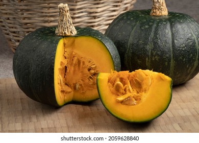 Fresh green whole Kabocha pumpkin and a cut close up on a cuttingboard