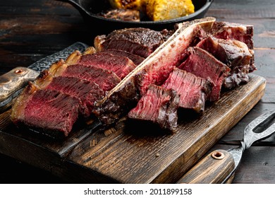 Fresh grilled meat. Grilled beef steak medium rare set, t bone or porterhouse cut, on wooden serving board, on old dark  wooden table background