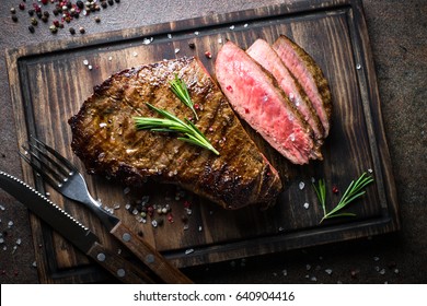 Fresh grilled meat. Grilled beef steak medium rare on wooden cutting board. Top view. - Shutterstock ID 640904416