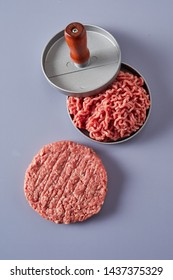 Fresh Ground Or Minced Raw Beef Being Compressed In A Patty Maker While Preparing Homemade Hamburgers With A Finished Circular Patty Alongside