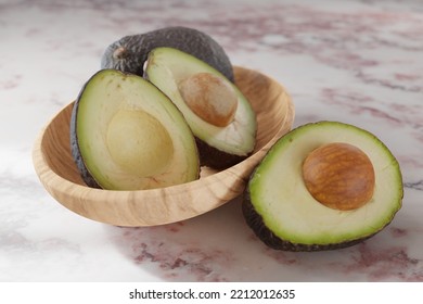 Fresh halved avocados in a bowl on a pink marble surface - Shutterstock ID 2212012635