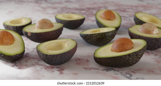 Fresh halved avocados on a pink marble surface - Shutterstock ID 2212012639