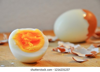 Fresh hard boiled eggs with shell beside on wooden board. Organic hard boiled eggs ready to eat. Wooden background. 