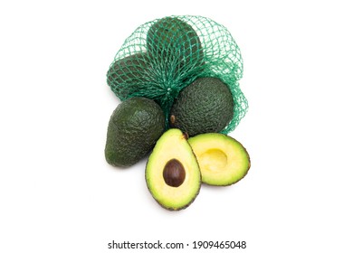 Fresh Hass avocados in a green mesh bag isolated on white. One avocado fruit is cut open.