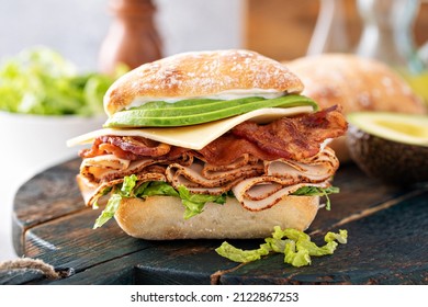 Fresh And Healthy Avocado Turkey Sandwich With Swiss Cheese And Bacon On Chiabatta Roll