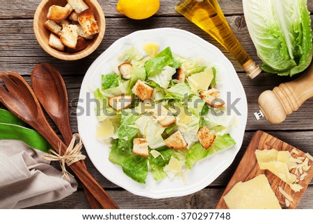 Fresh healthy caesar salad cooking on wooden table. Top view