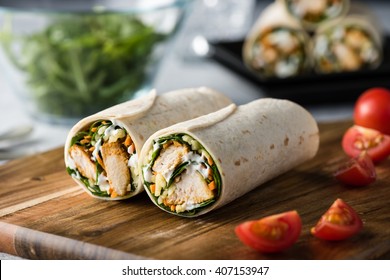 Fresh healthy chargrilled tandoori chicken wrap with tzatziki, cheese, baby spinach and carrots 