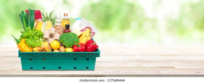 Fresh Healthy Food And Vegetables From Grocery Store In Tray Box On Wood Tabletop In Blur Green Natural Bokeh Banner Background With Copy Space