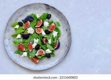 Fresh Healthy Mixed Summer Salad With Figs, White Cheese, Arugula And Black Olives On Gray Ceramic Plate On Gray Background. Top Down View. Close-up. Copy Space.