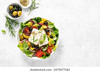 Fresh healthy vegetable Mediterranean food salad of Greek feta cheese, tomato, olives, pepper, lettuce and green basil leaves, top view - Powered by Shutterstock