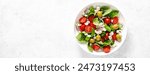 Fresh healthy vegetable Mediterranean salad of feta cheese, tomato, olives, green pepper and green basil leaves, banner, top view