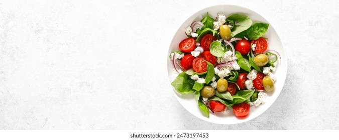 Fresh healthy vegetable Mediterranean salad of feta cheese, tomato, olives, green pepper and green basil leaves, banner, top view