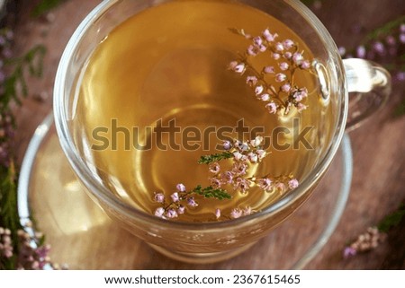 Fresh heather flowers in a transparent cup of herbal tea, close up