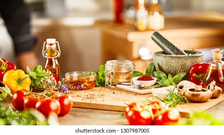 Fresh herbs, spices vegetables, pestle and mortar with olive oil on a kitchen counter in a restaurant in a wide angle banner - Powered by Shutterstock