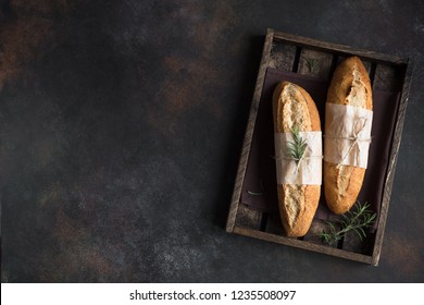 Fresh homemade artisan bread with rosemary on rustic  background, top view, copy space. Sourdough mini baguette bread. - Powered by Shutterstock