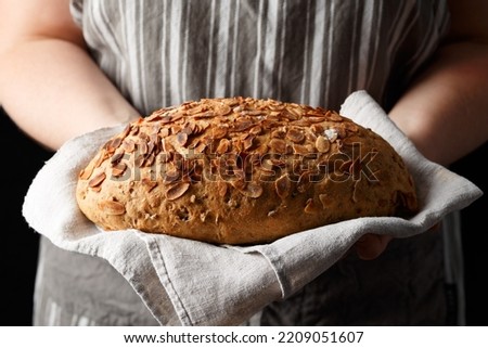 Fresh Homemade bloomer bread with almond flakes in bakers hands