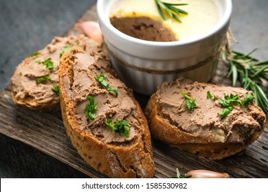 Fresh homemade chicken liver pate in ceramic bowl or ramekin and baguette slices with pate on the serving board, selective focus. 