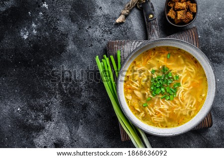 Fresh homemade chicken soup with noodle at table. Black background. Top view. Copy space