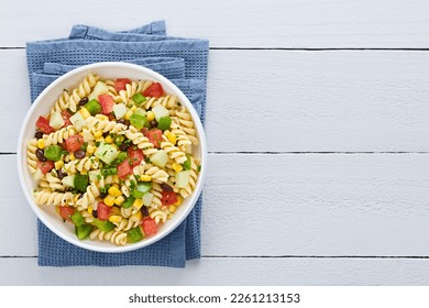 Fresh homemade colorful vegan fusilli pasta salad with beans, corn, tomato, cucumber, green bell pepper, photographed overhead on white wood with copy space on the side (Selective Focus on the dish) - Powered by Shutterstock